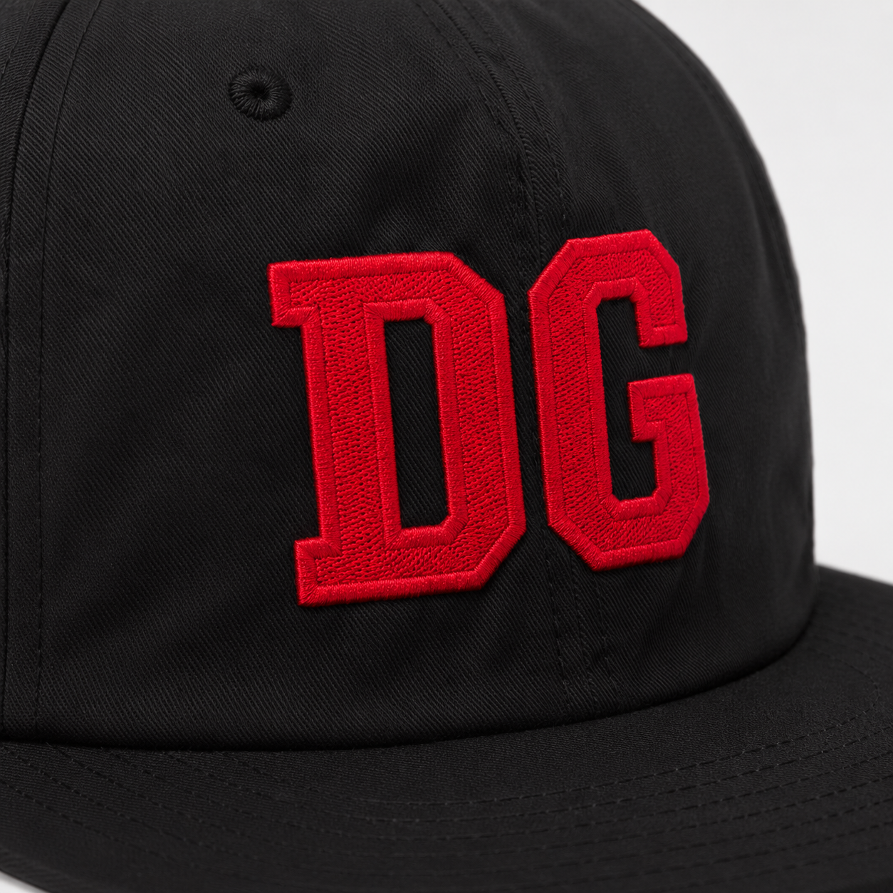 Close-up of red raised 3D embroidered logo on a black nylon custom snapback hat.