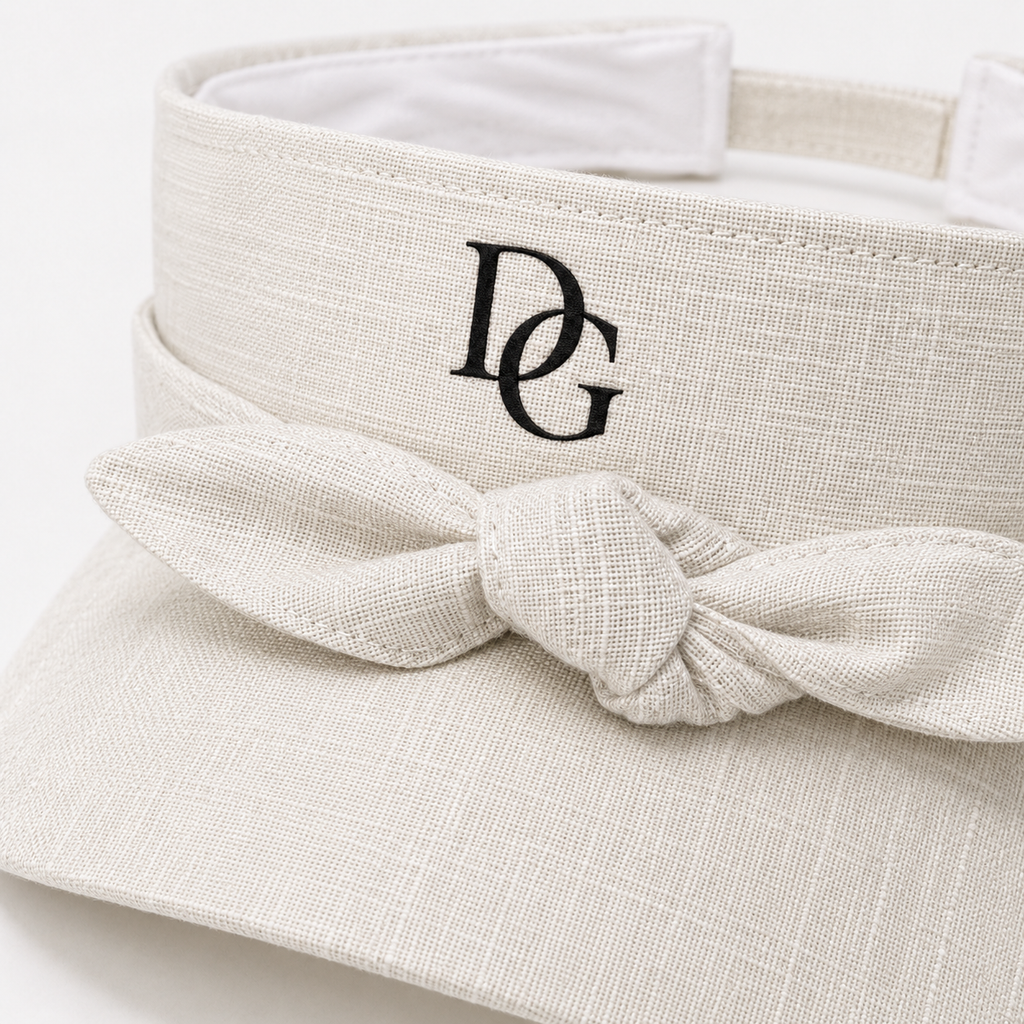 Close-up of custom embroidered DG logo and bow tie detail on a textured polyester sports visor.