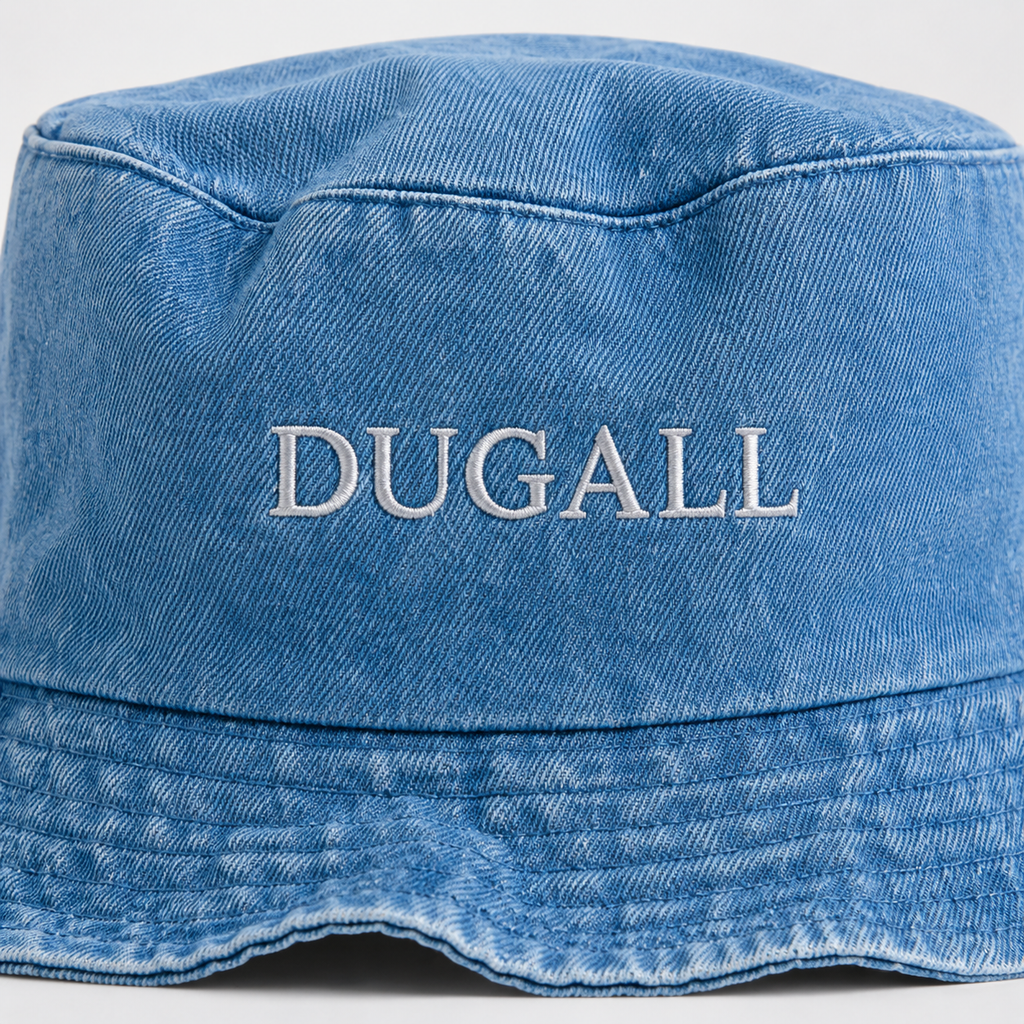 Close-up of flat embroidery DUGALL logo on washed denim canvas bucket hat showing fabric texture and stitching detail.