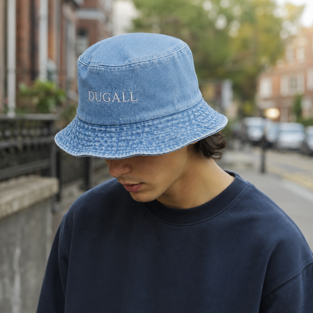 Male model wearing a washed denim bucket hat with custom embroidered logo in a casual streetwear setting.