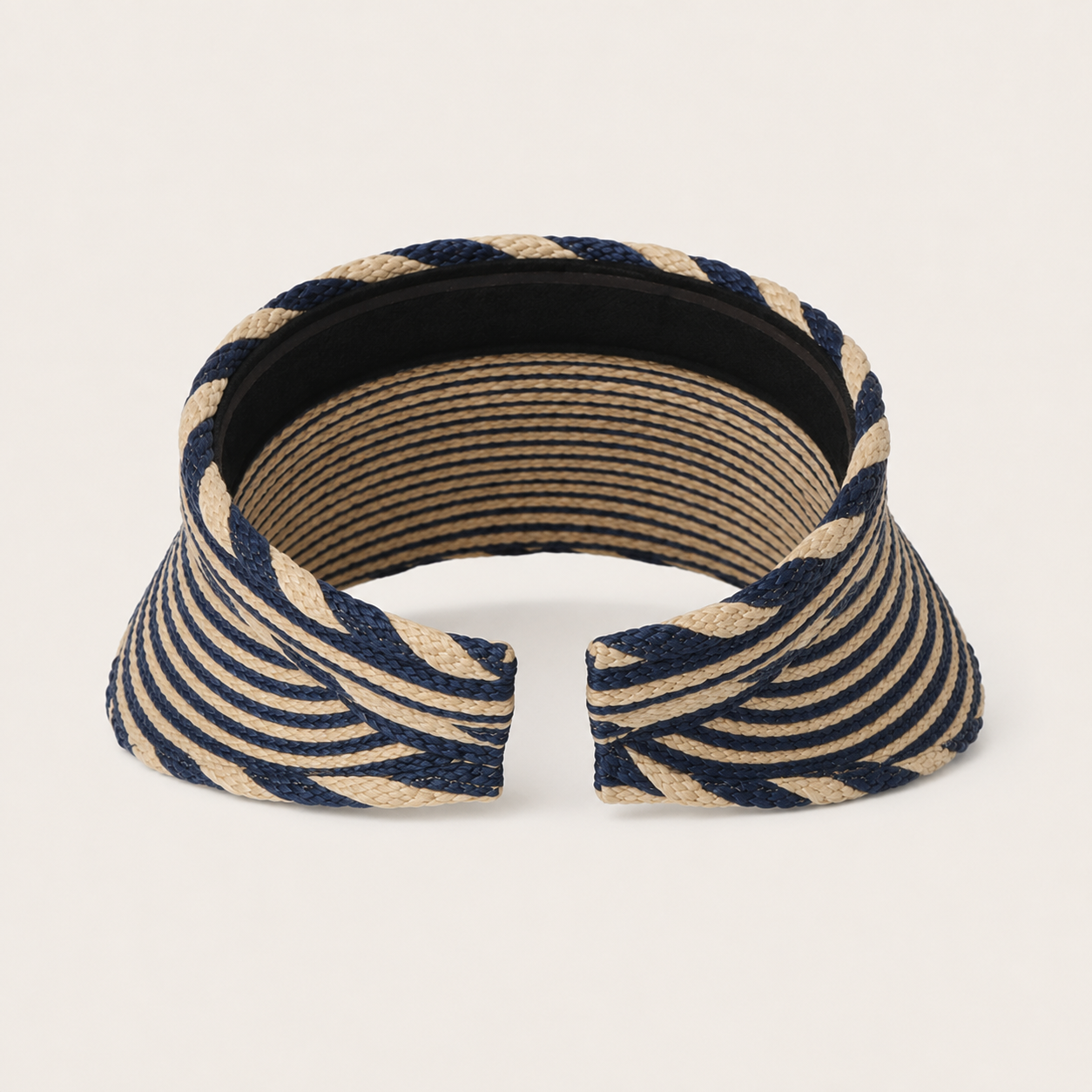 A woven visor-style headband with a navy blue and beige striped pattern, shown against a plain off-white background.