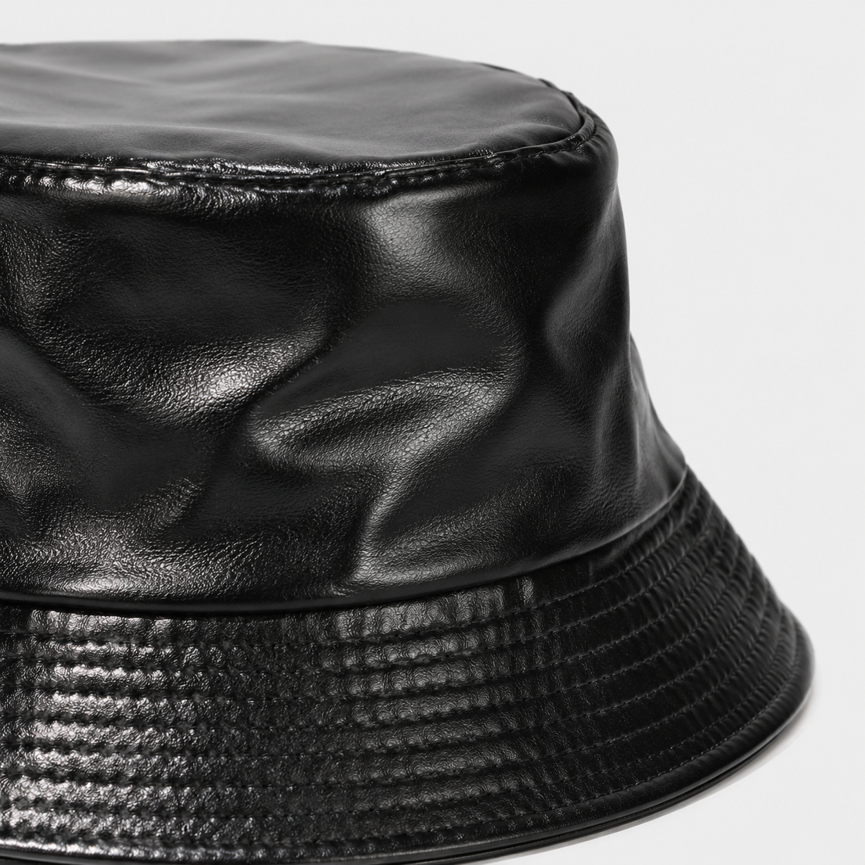 Close-up of glossy PU leather texture on a black faux leather bucket hat