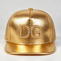 Front view of a custom gold PU 5 panel flat brim cap with embossed texture and rhinestone logo.