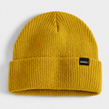 Mustard yellow acrylic ribbed beanie with folded cuff and custom woven label logo.