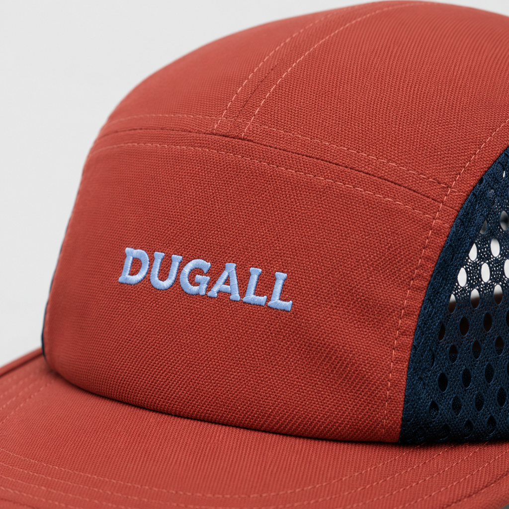 Close-up of light blue custom embroidered logo on orange cotton front panel with navy breathable mesh side panel.
