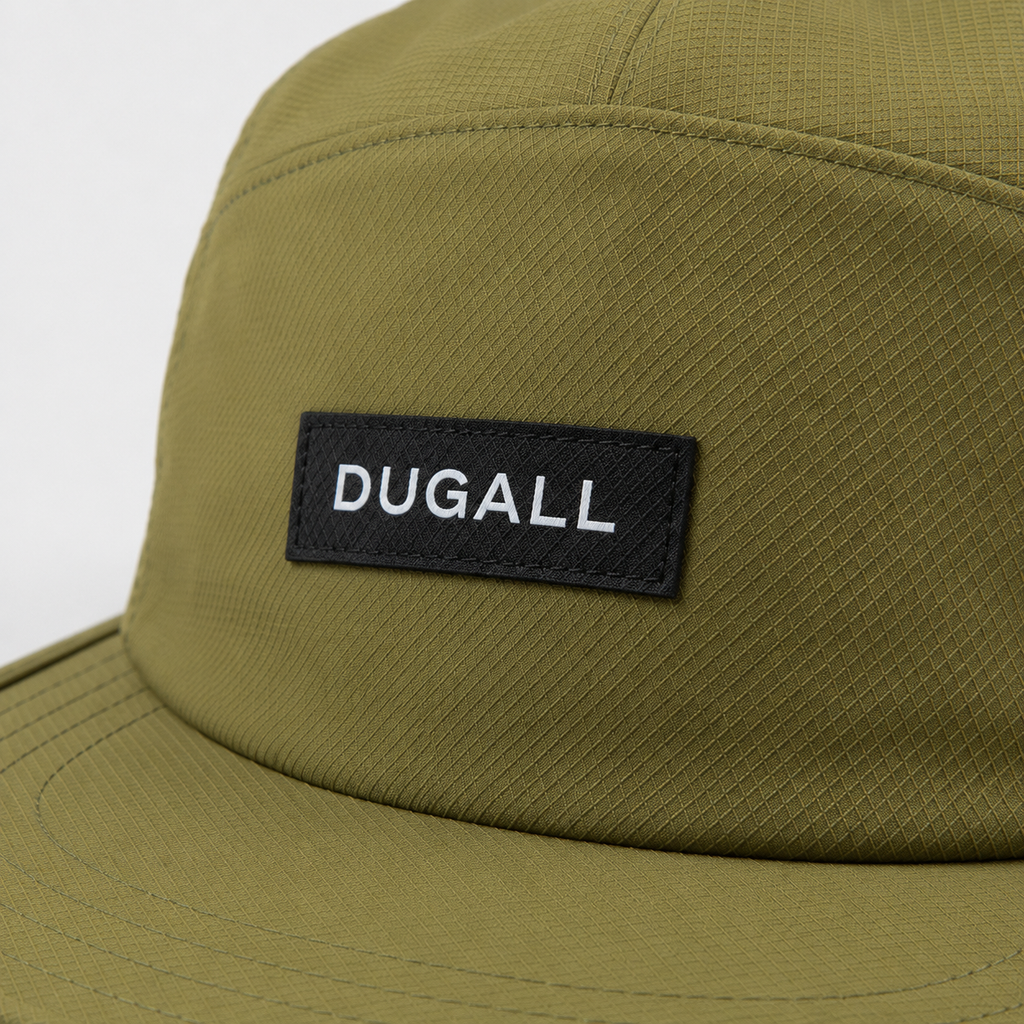 Close-up of custom black label logo on olive green polyester outdoor 5 panel cap with textured quick-dry fabric.