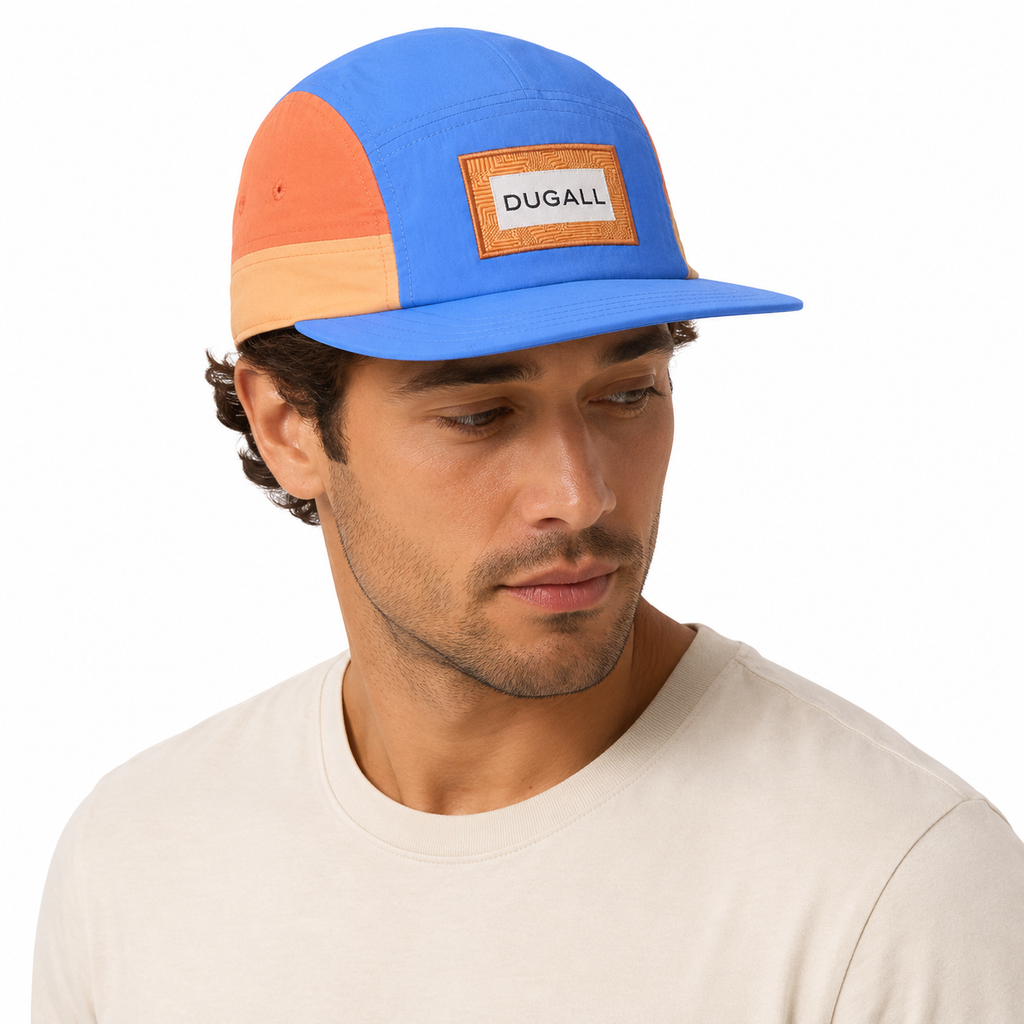 Male model wearing a blue and orange custom color block nylon 5 panel cap with patch label logo.