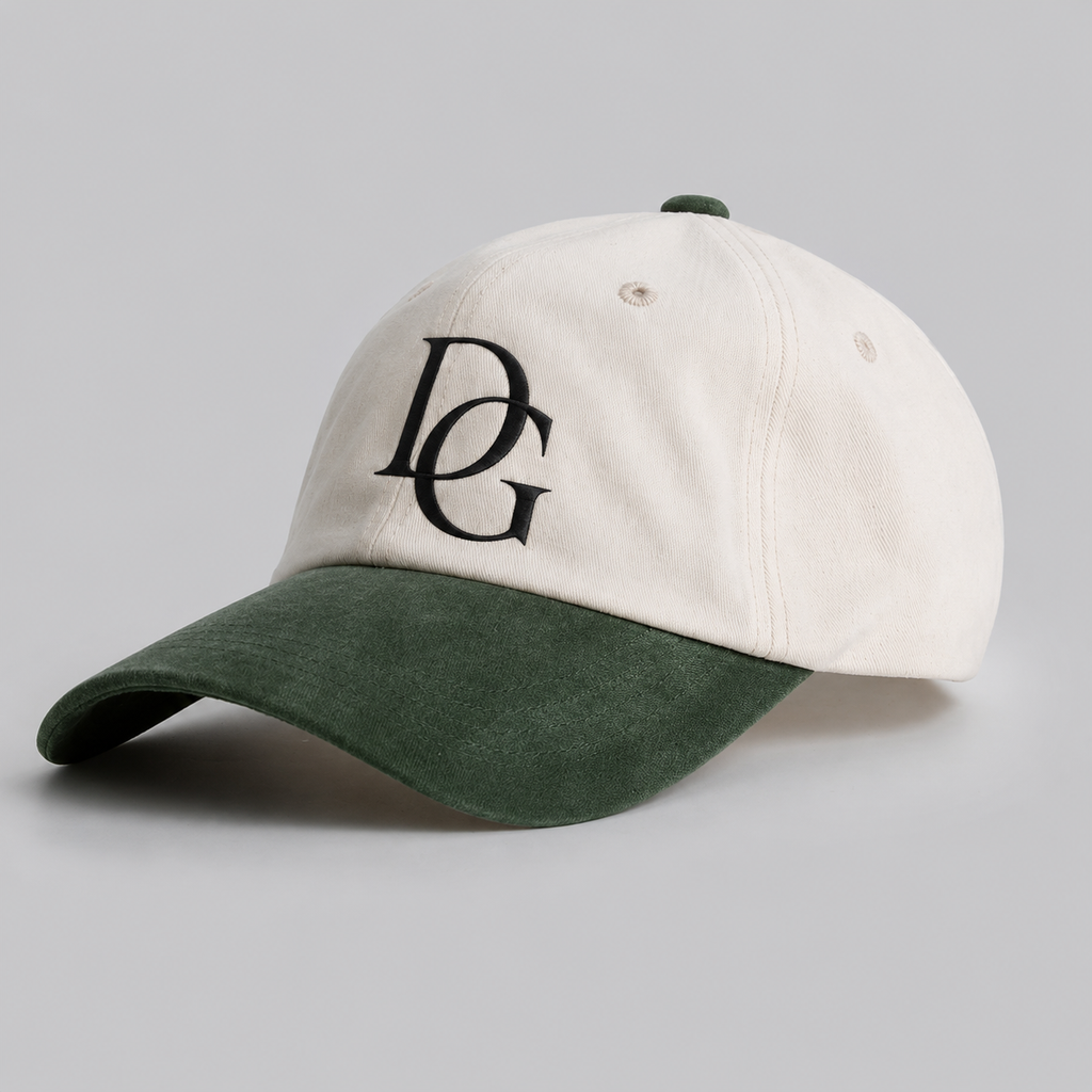 Angled view of a cream cotton dad hat with green faux suede curved brim and custom embroidered logo.