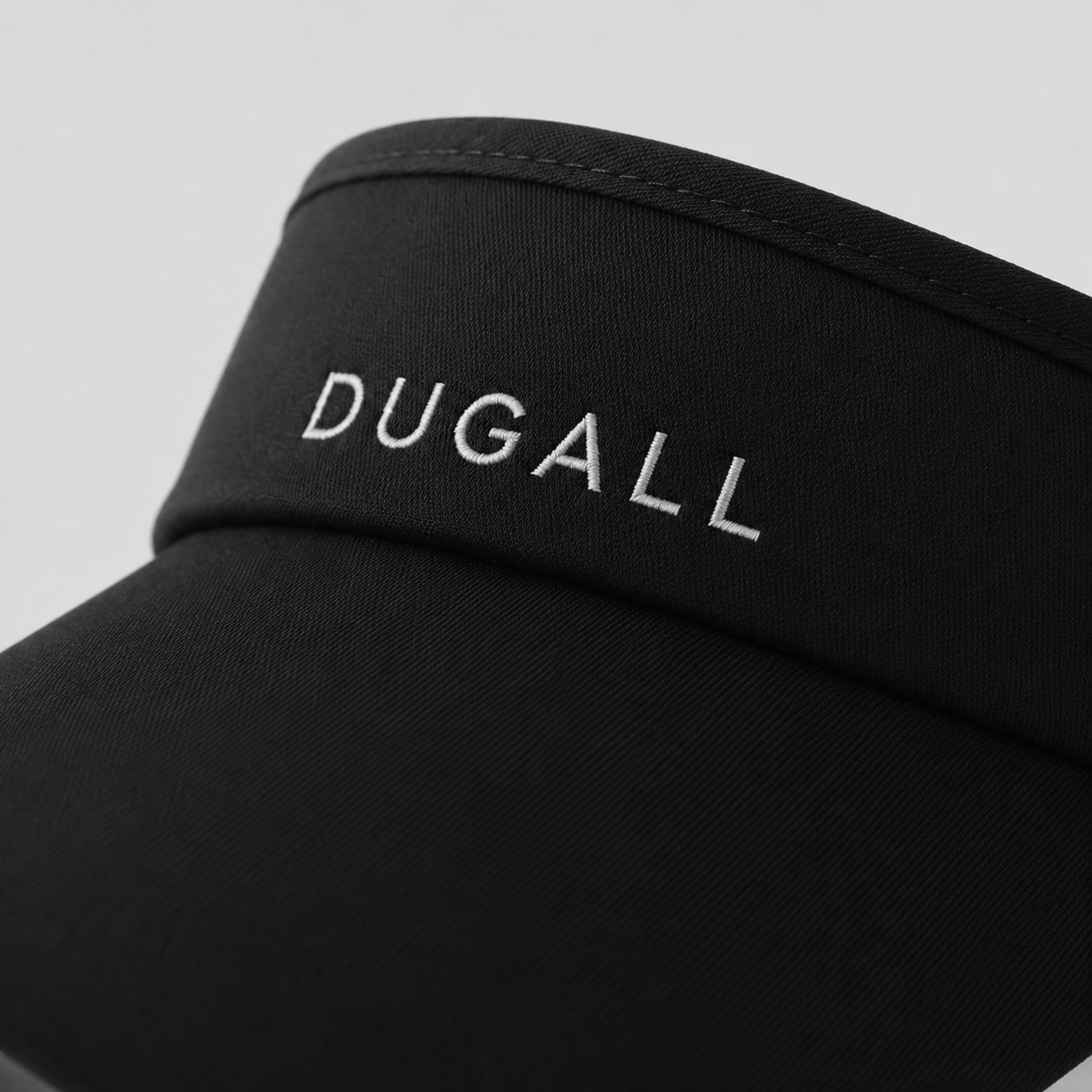 Close-up detail of embroidered DUGALL logo on a black custom sports visor showing premium stitching and clean finish