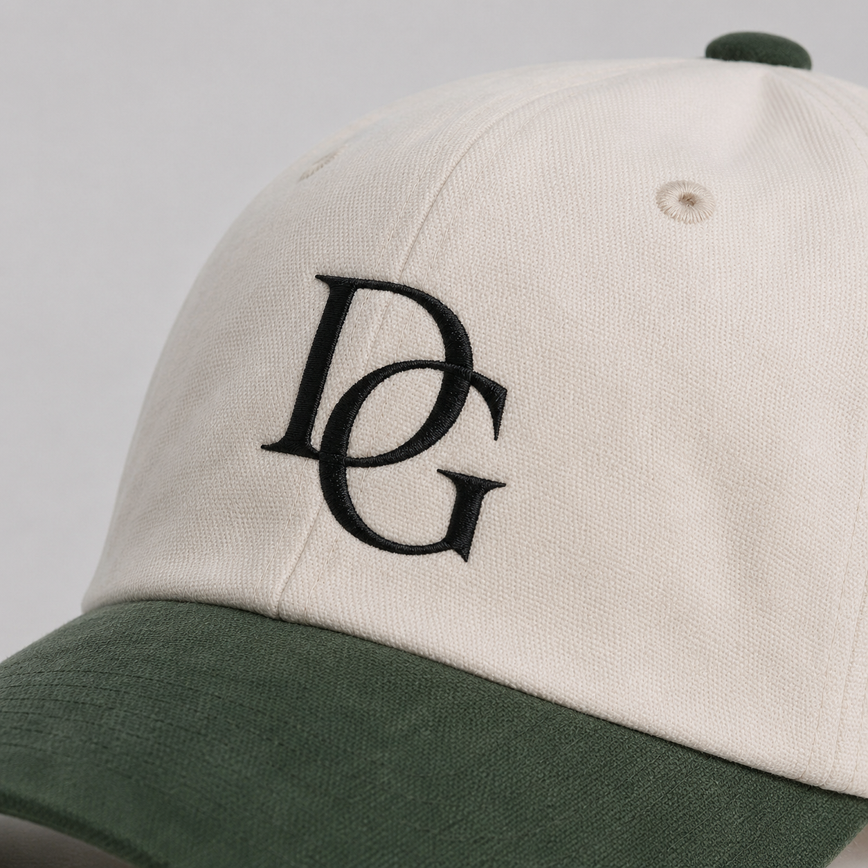 Close-up of black custom embroidery logo on a cotton dad hat with green faux suede brim.