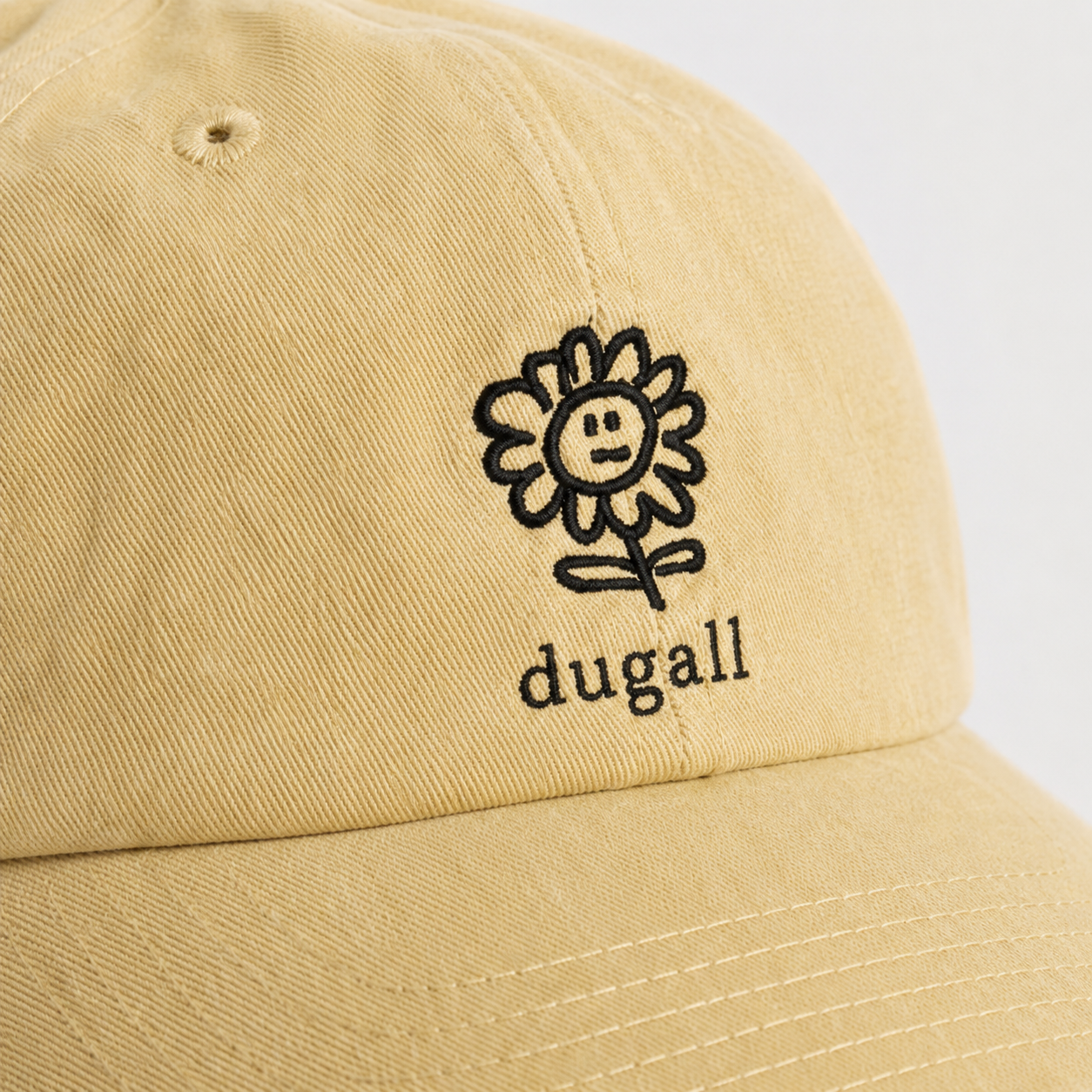 Close up of custom embroidery logo on a beige 100% cotton dad hat showing clean stitching detail