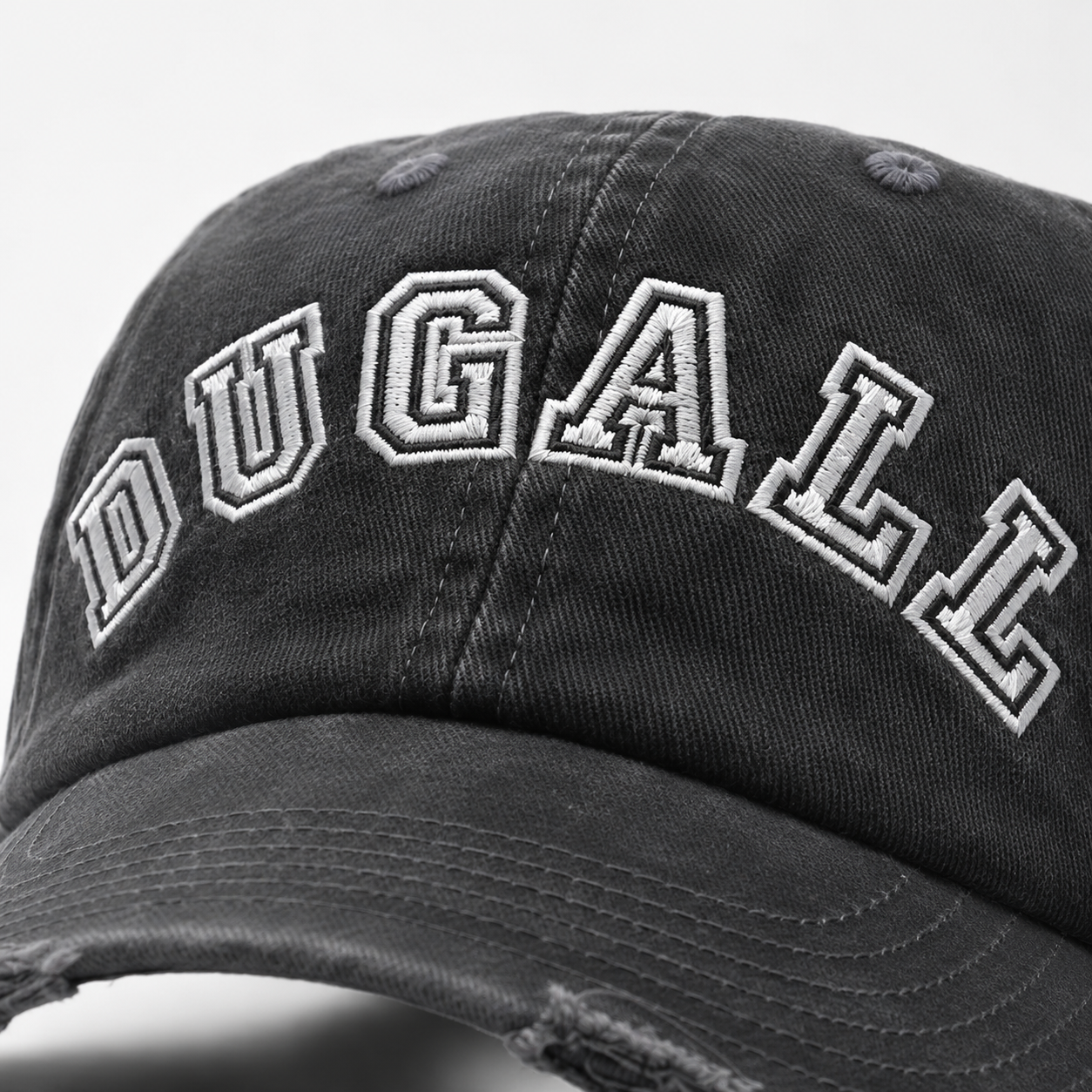 Close up of white embroidered DUGALL logo on a black washed 100% cotton dad hat.