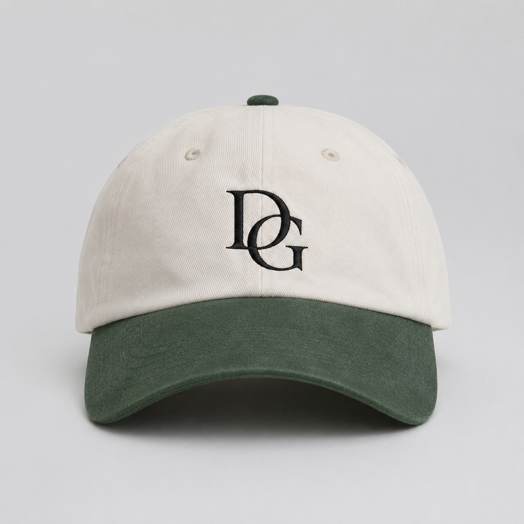 Front view of a custom dad hat with cream cotton crown, green faux suede brim, and black embroidered DG logo.