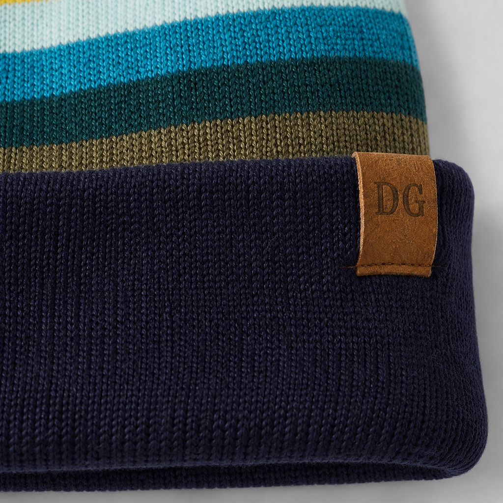 Close-up of leather patch logo on a retro striped acrylic ski beanie with navy folded cuff.