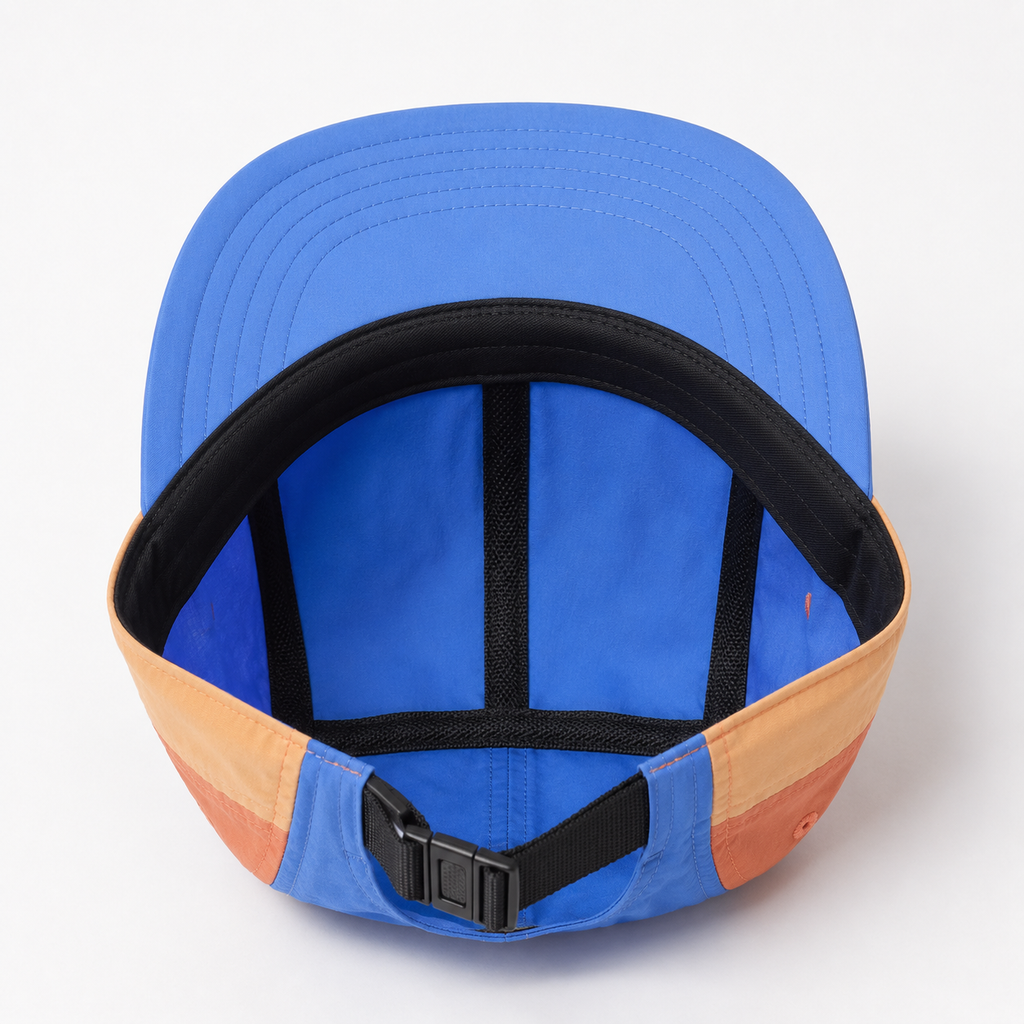 Interior view of a custom nylon 5 panel cap showing flat brim, inner taping, adjustable strap, and color block construction.