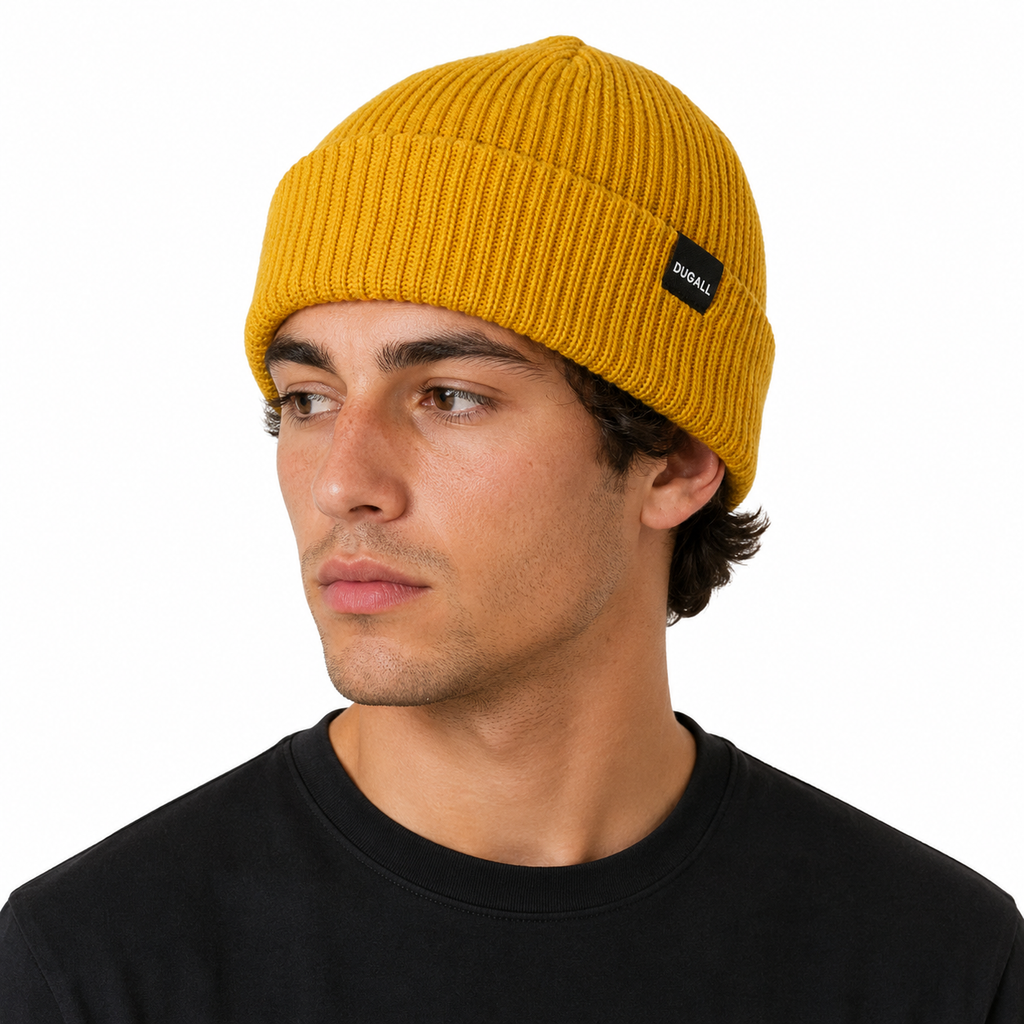 Male model wearing a mustard yellow acrylic ribbed beanie with custom woven label logo.