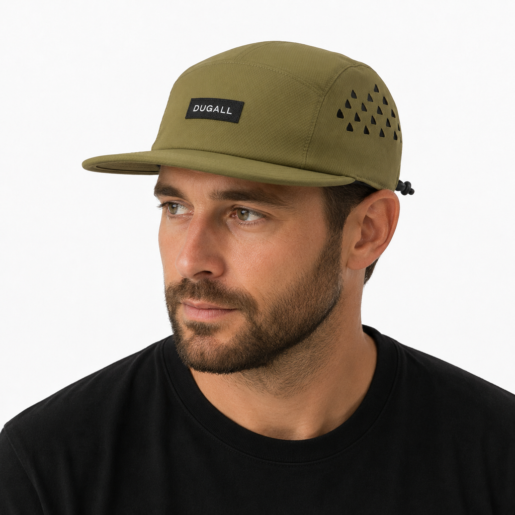 Male model wearing an olive green custom outdoor 5 panel cap with label logo, flat brim, and breathable side panels.