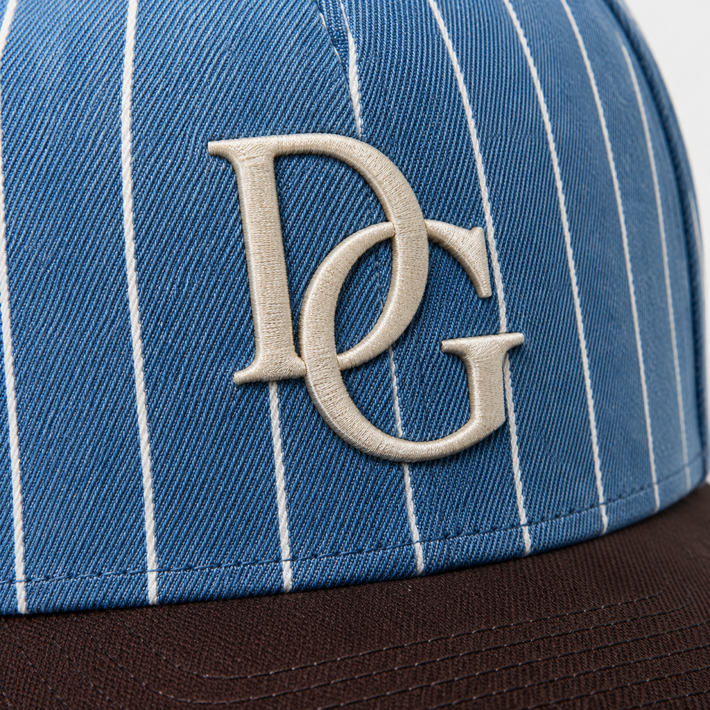 Close-up of raised custom embroidery logo on a blue pinstripe dad hat with brown curved brim.