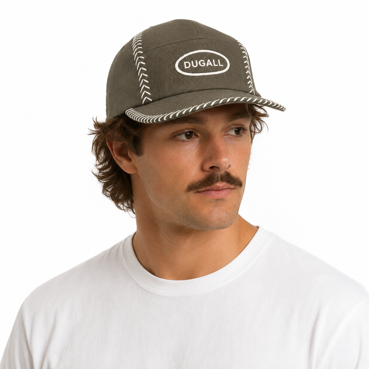 A man wearing a dark olive green baseball cap with white contrast stitching and a white embroidered oval logo that reads 'DUGALL'. He is wearing a plain white t-shirt against a clean white background.