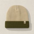Front view of a short cuffed color block knit beanie in cream and olive green with minimalist woven label detail