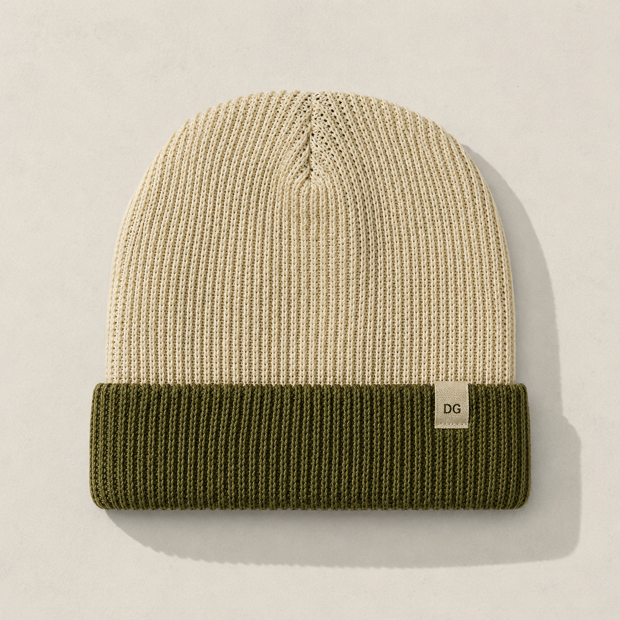 Front view of a short cuffed color block knit beanie in cream and olive green with minimalist woven label detail