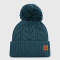 Front view of a teal custom winter beanie with pom pom, cable knit texture, folded cuff, and leather patch logo.