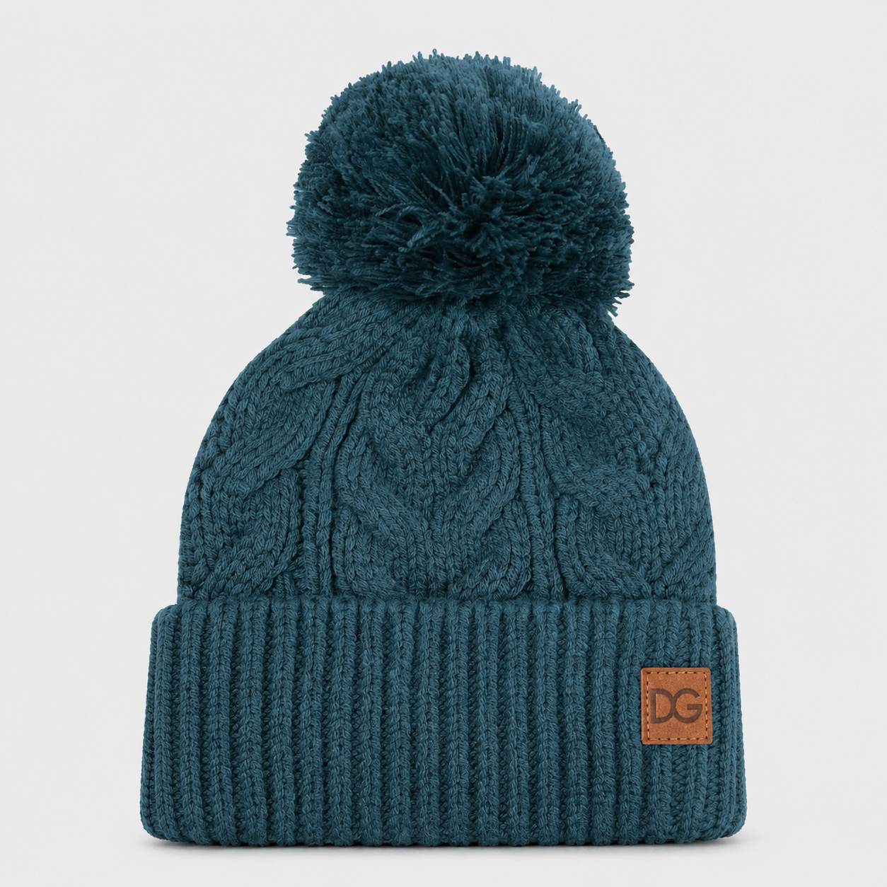 Front view of a teal custom winter beanie with pom pom, cable knit texture, folded cuff, and leather patch logo.