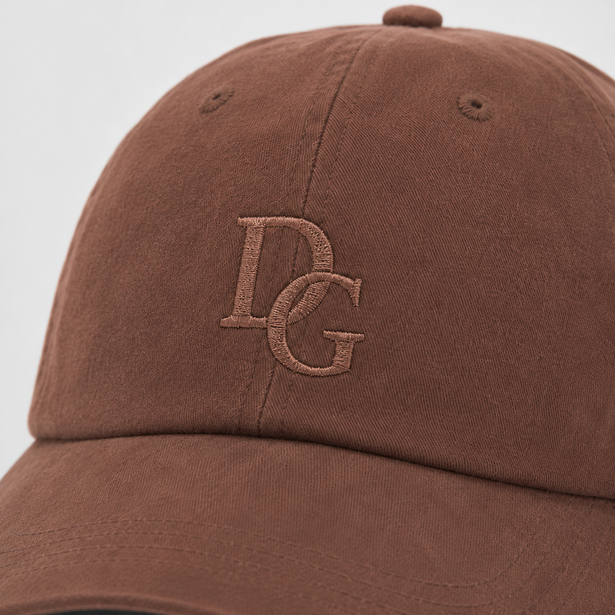 Close-up of tone-on-tone embroidered DG logo on a coffee brown washed cotton dad hat.