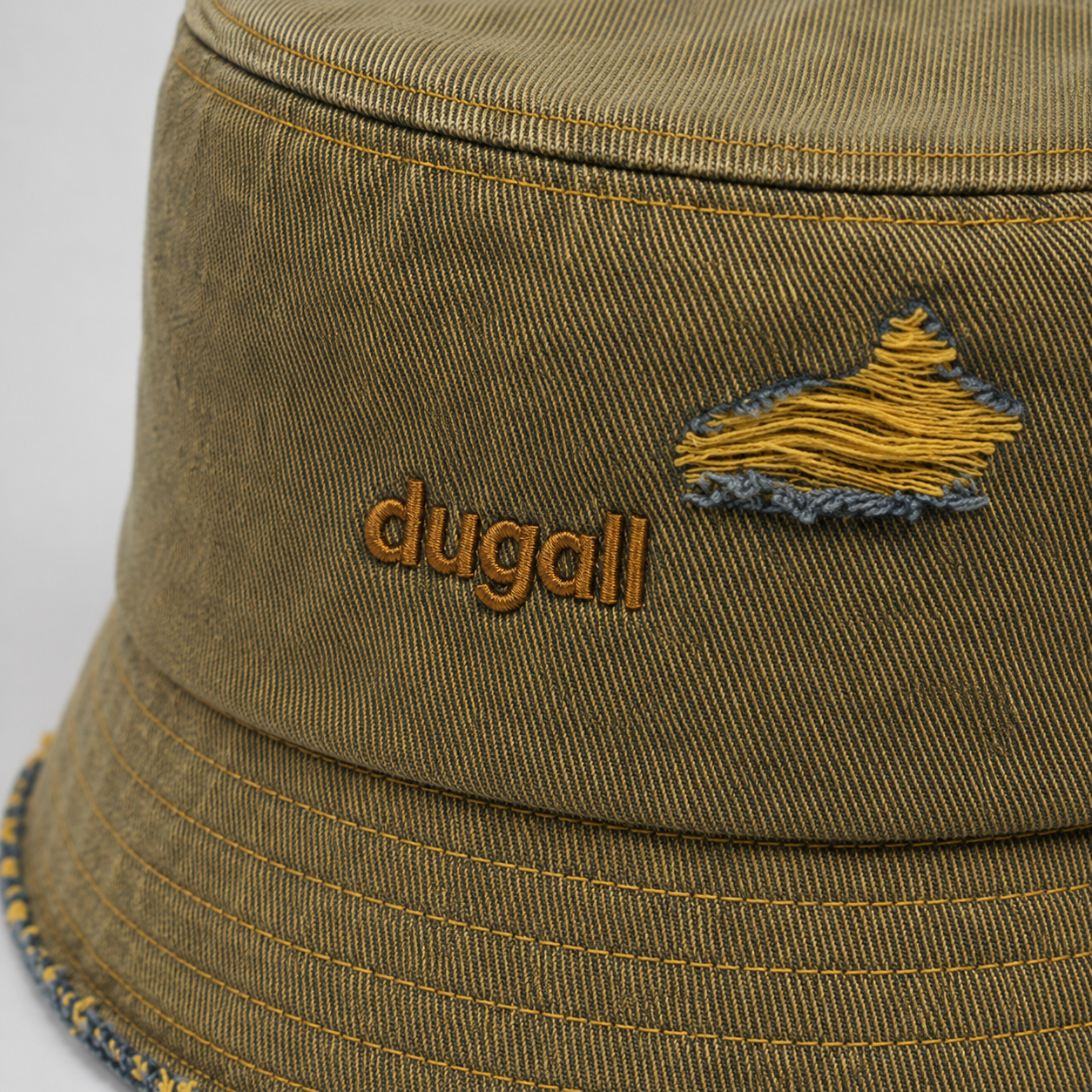 Close-up of custom embroidery logo on a washed 100% cotton bucket hat with distressed fabric texture