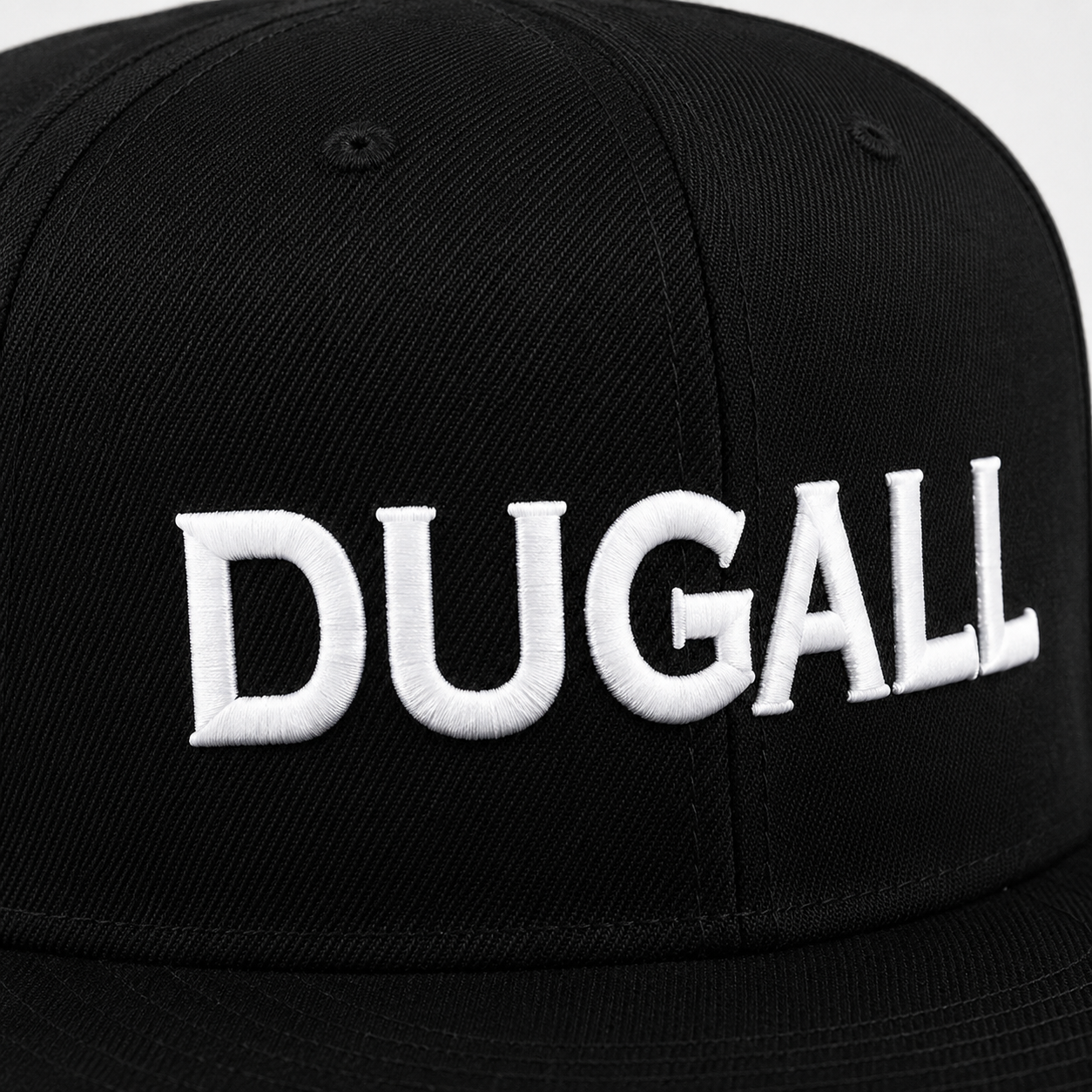 Close-up of white custom embroidered logo on a black cotton snapback hat with flat brim.
