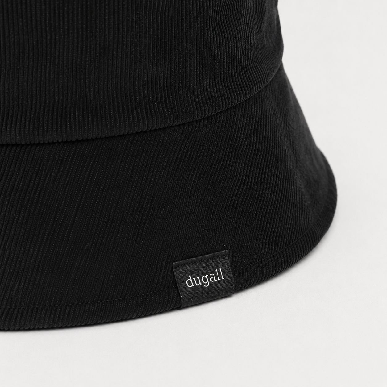 Close-up of custom woven side label logo on black cotton bucket hat with ribbed texture